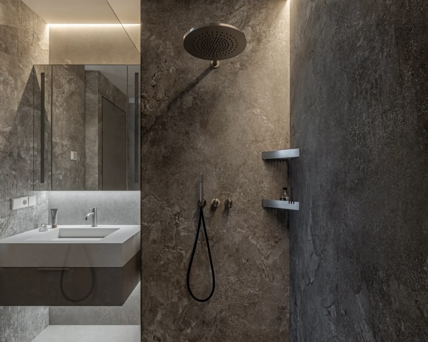 Фото сучасної душової кімнати, оздобленої сірим мармуром. У стелю вбудована підсвітка. На стіні — тропічний душ, ручна лійка та дві невеликі полички. Поруч — дзеркало і підвісна тумба з раковиною.