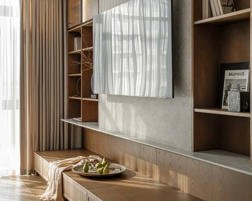 Інтер'єр вітальні з ТВ-зоною. Стіна, де висить телевізор, оздоблена дерев'яними панелями. Під телевізором — низька дерев'яна тумба з шухлядами.